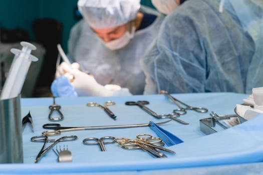 Close-up of surgical instruments on table with surgeons in the background preparing for surgery.
